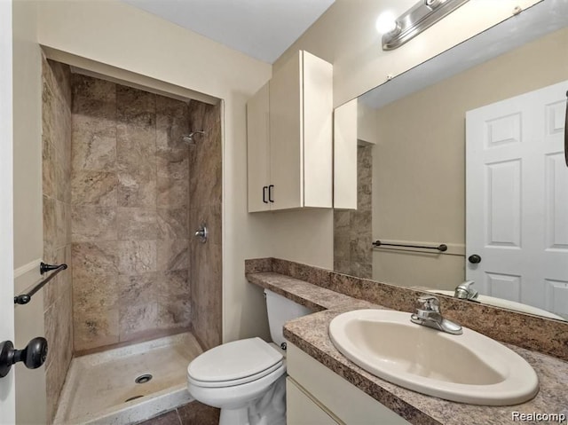 bathroom featuring tile patterned flooring, vanity, toilet, and tiled shower