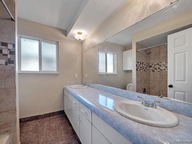 bathroom featuring vanity, a tile shower, and a wealth of natural light