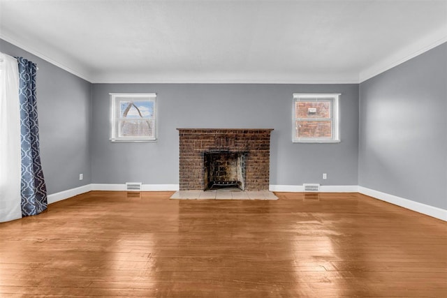 unfurnished living room featuring light hardwood / wood-style floors, ornamental molding, and a brick fireplace