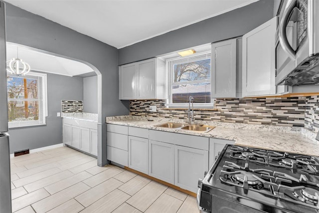 kitchen featuring gas range, decorative backsplash, sink, and a healthy amount of sunlight