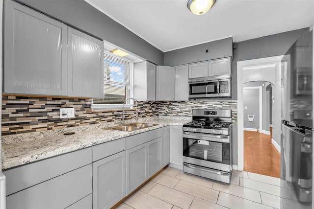 kitchen featuring light stone countertops, gray cabinetry, stainless steel appliances, sink, and light hardwood / wood-style floors