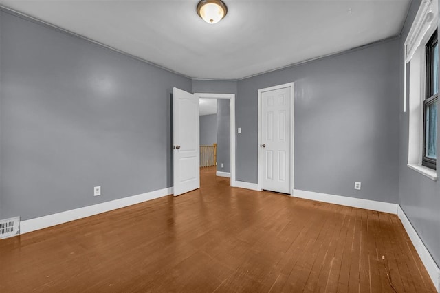 unfurnished bedroom with hardwood / wood-style flooring, ornamental molding, and a closet