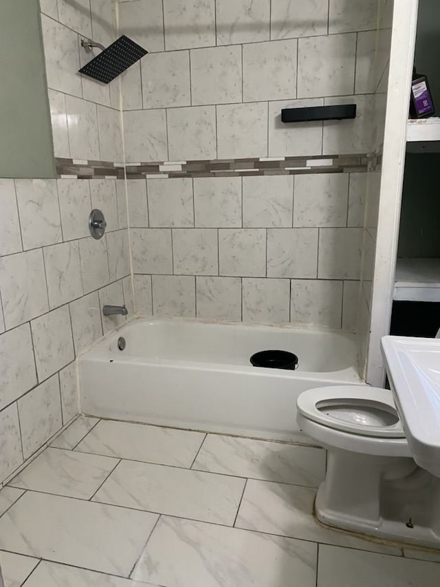 bathroom featuring toilet and tiled shower / bath