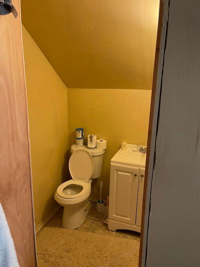 bathroom featuring tile patterned floors, vanity, toilet, and lofted ceiling