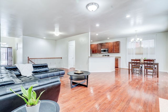 living room with light hardwood / wood-style floors and an inviting chandelier