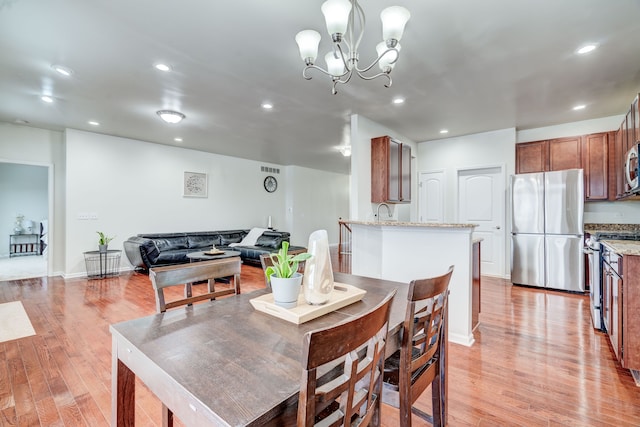 dining area featuring sink, light hardwood / wood-style floors, and an inviting chandelier