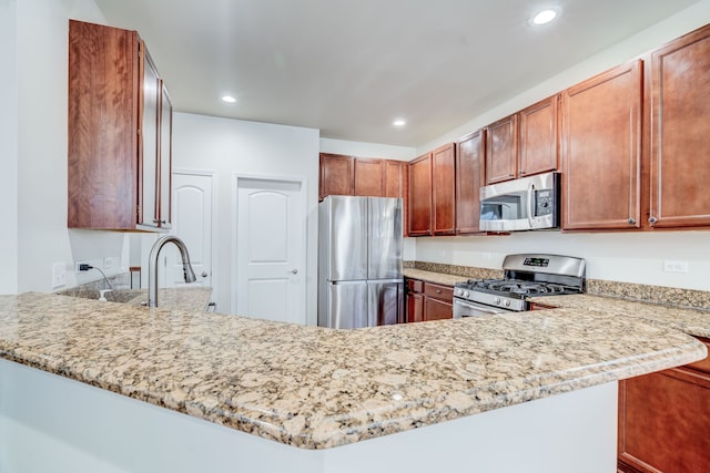 kitchen with sink, light stone counters, kitchen peninsula, and stainless steel appliances