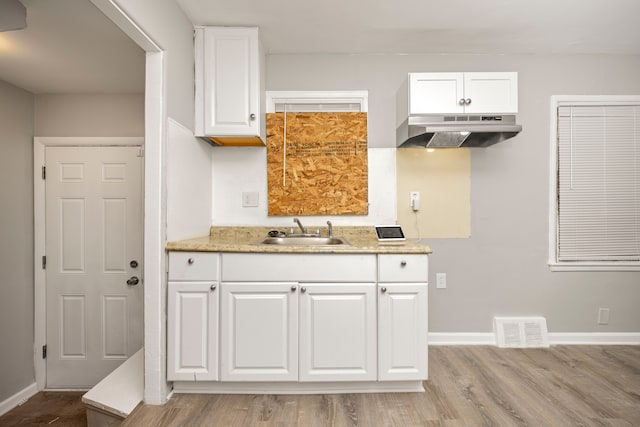 kitchen featuring sink, white cabinets, range hood, and light hardwood / wood-style flooring