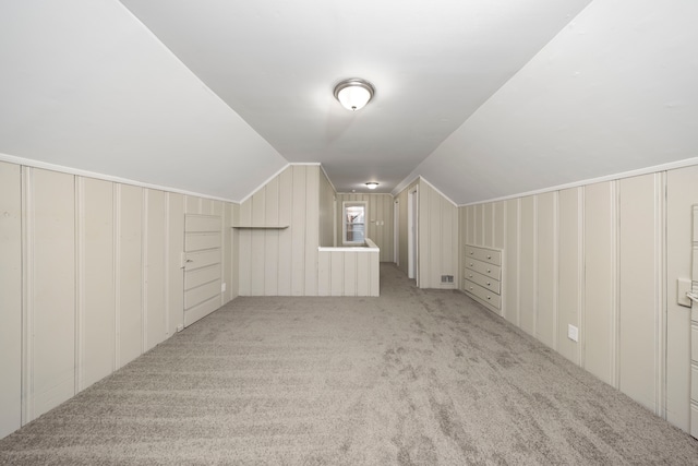 additional living space featuring light colored carpet and lofted ceiling