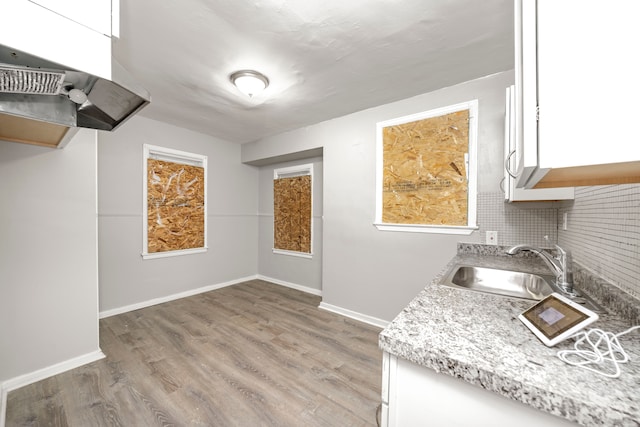 kitchen with sink, backsplash, white cabinets, and light wood-type flooring