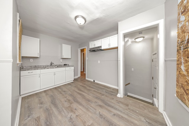 kitchen with sink, backsplash, light hardwood / wood-style floors, and white cabinets