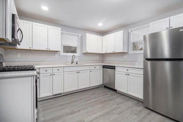 kitchen featuring white cabinets, light hardwood / wood-style floors, sink, and stainless steel appliances