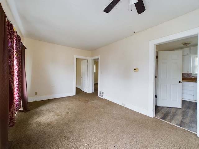 unfurnished bedroom with ceiling fan and dark carpet