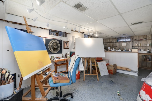 office space with a paneled ceiling and wood walls