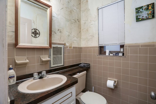 bathroom with vanity, toilet, and tile walls