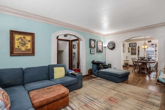 living room with wood-type flooring, ornamental molding, and an inviting chandelier