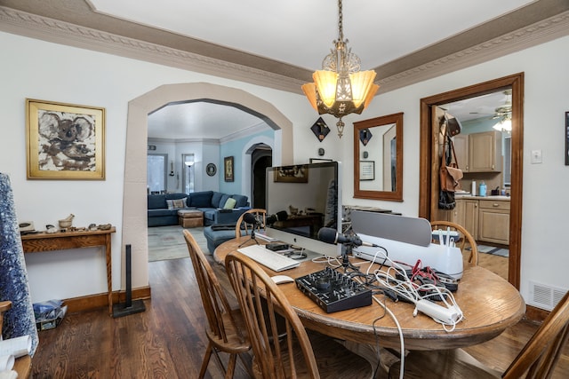 dining room featuring a wood stove, dark hardwood / wood-style flooring, ceiling fan with notable chandelier, and ornamental molding