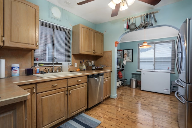 kitchen with sink, hanging light fixtures, stainless steel appliances, and light hardwood / wood-style floors