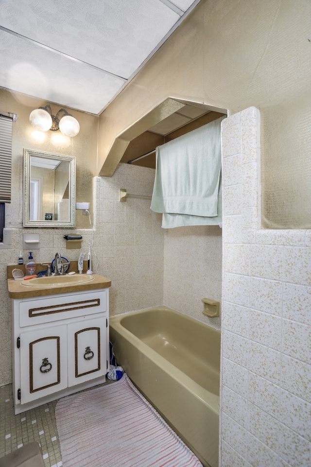 bathroom featuring vanity, tile patterned floors, tile walls, and a bathing tub