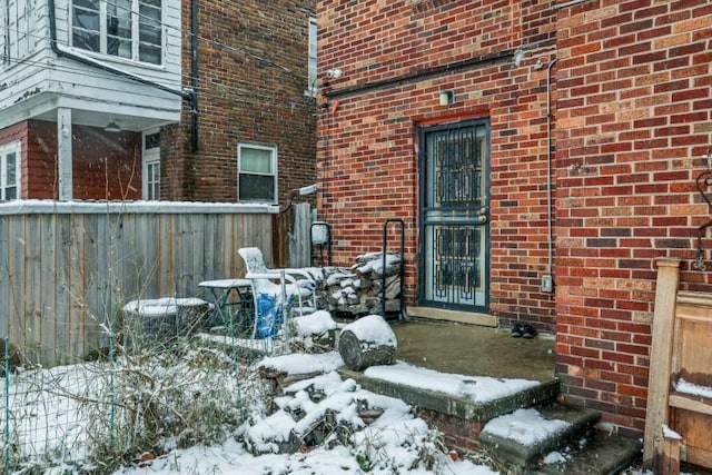 snow covered property entrance with cooling unit