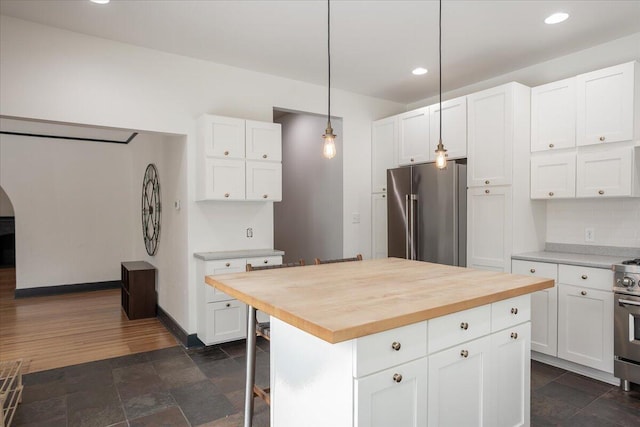 kitchen with white cabinets, decorative light fixtures, butcher block countertops, and appliances with stainless steel finishes