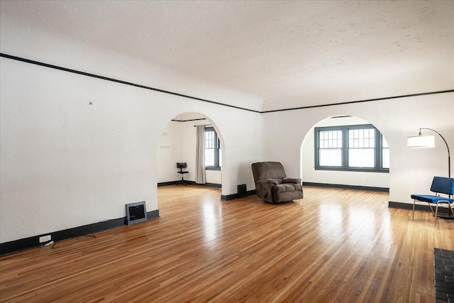 unfurnished room with light hardwood / wood-style floors, ornamental molding, and a textured ceiling