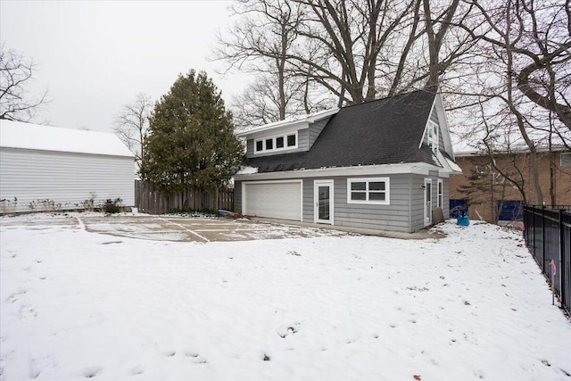 snow covered rear of property featuring a garage