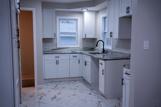 kitchen with sink, white cabinets, and dark stone counters