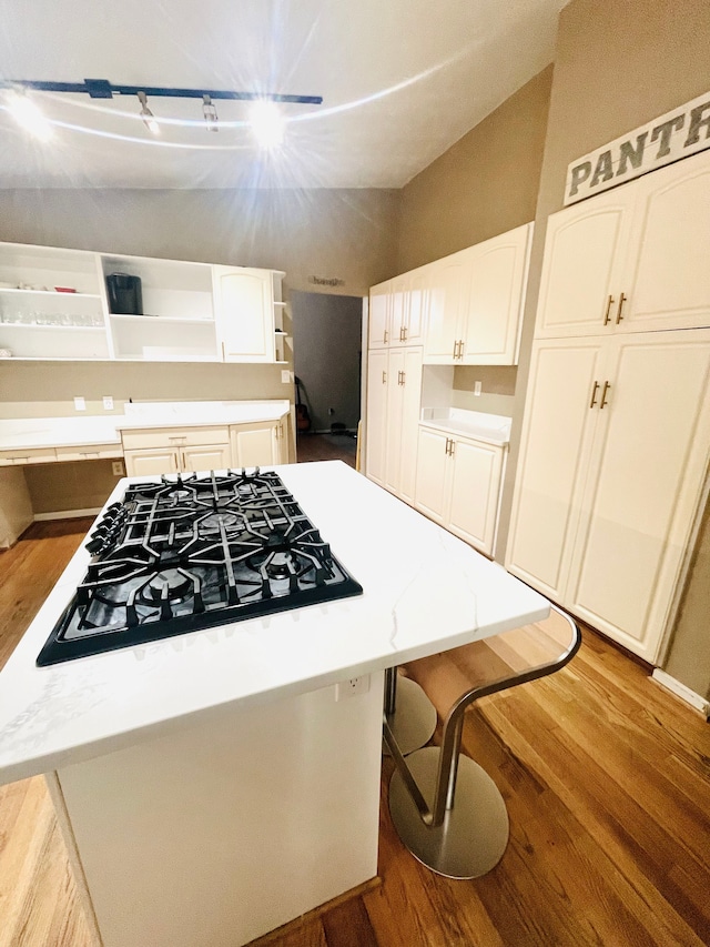 kitchen with white cabinets, a kitchen island, light hardwood / wood-style floors, and gas cooktop