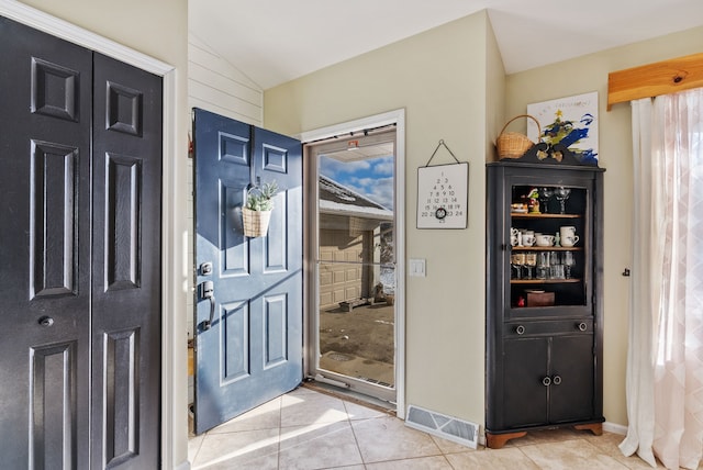 tiled foyer featuring wood walls and vaulted ceiling