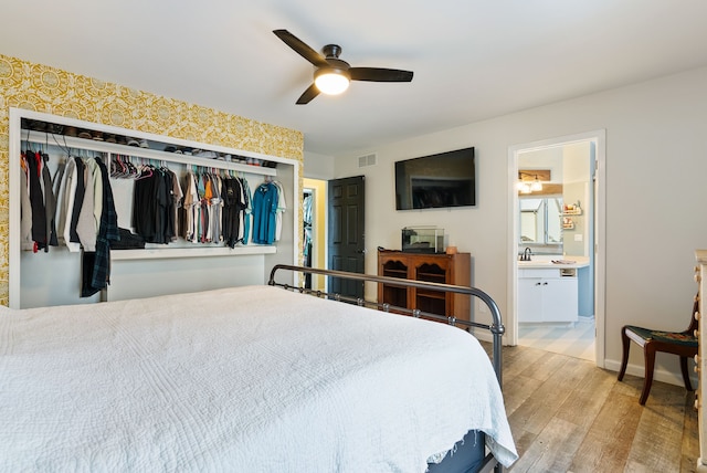 bedroom featuring ensuite bathroom, light hardwood / wood-style flooring, a closet, and ceiling fan