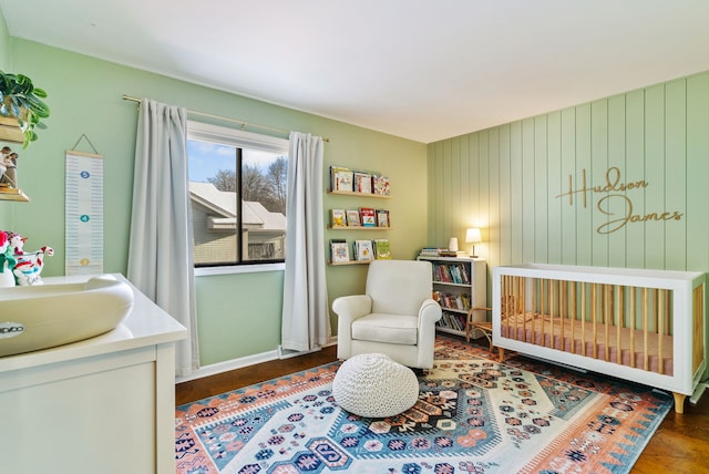 bedroom with dark hardwood / wood-style floors, sink, and a nursery area