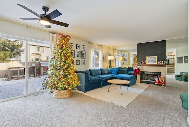 carpeted living room with ceiling fan and a large fireplace