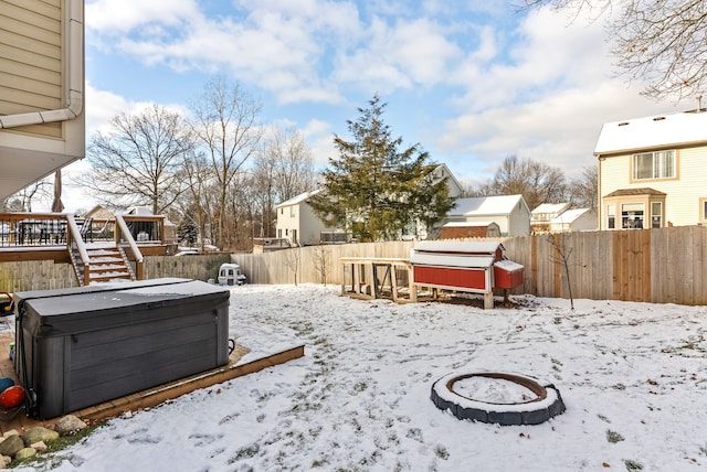 yard covered in snow featuring a wooden deck, a hot tub, and an outdoor fire pit