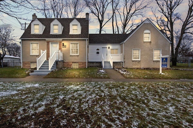 cape cod home featuring a lawn