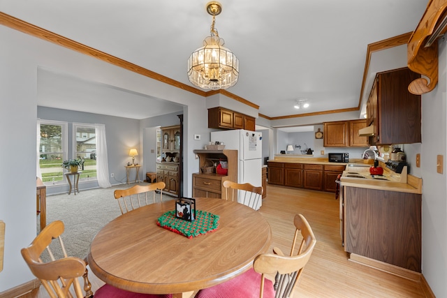 dining room with a notable chandelier, light wood-type flooring, and crown molding