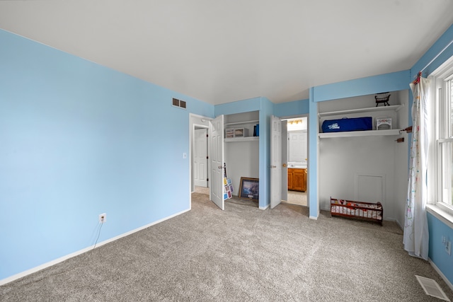 unfurnished bedroom featuring ensuite bathroom and carpet