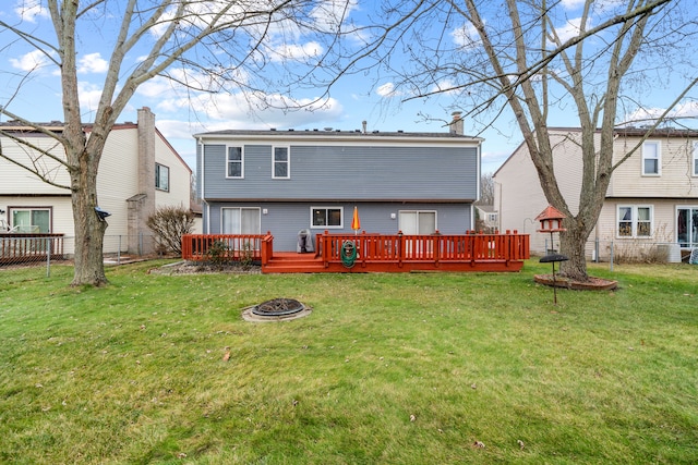 rear view of property with a lawn, a deck, and an outdoor fire pit