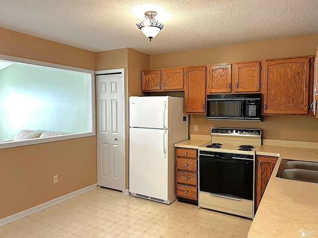 kitchen with a textured ceiling, white appliances, and sink