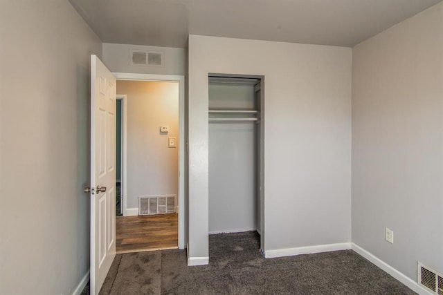 unfurnished bedroom featuring dark colored carpet and a closet