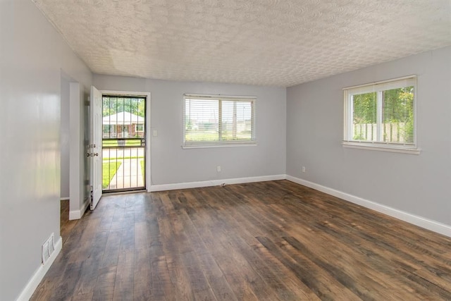 unfurnished room with a textured ceiling and dark hardwood / wood-style floors