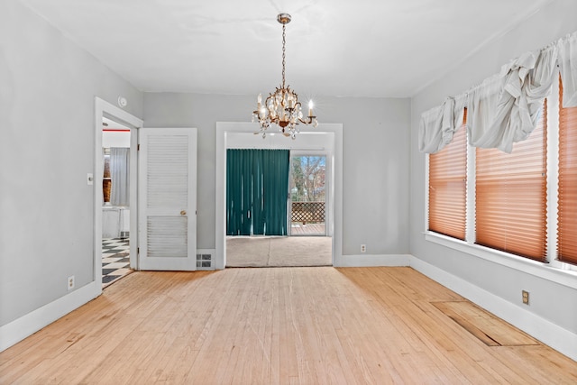 empty room with hardwood / wood-style floors and a notable chandelier