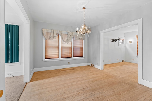 unfurnished dining area with hardwood / wood-style floors and a notable chandelier