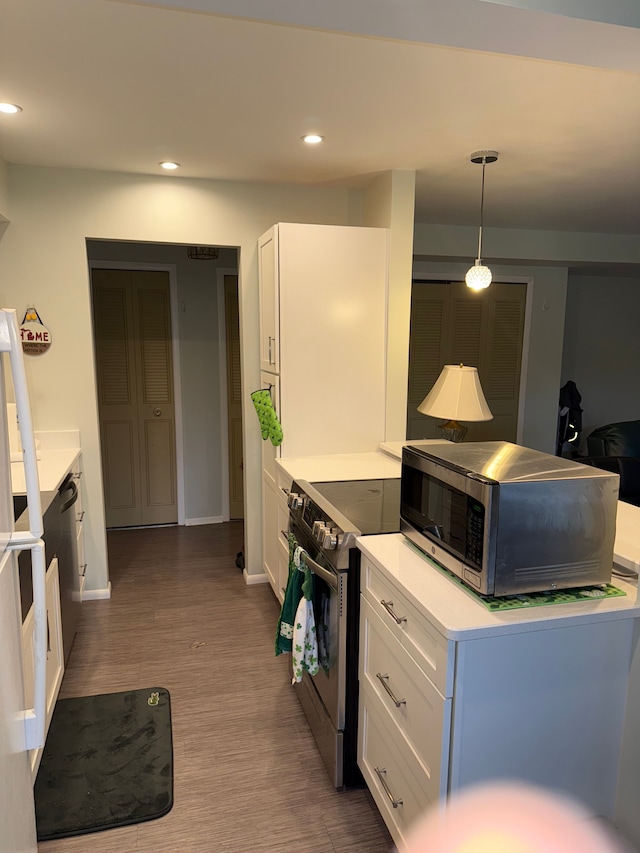 kitchen featuring white cabinets, appliances with stainless steel finishes, pendant lighting, and hardwood / wood-style floors