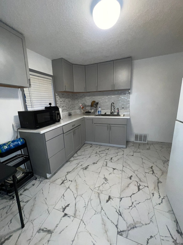 kitchen with backsplash, gray cabinets, sink, and a textured ceiling