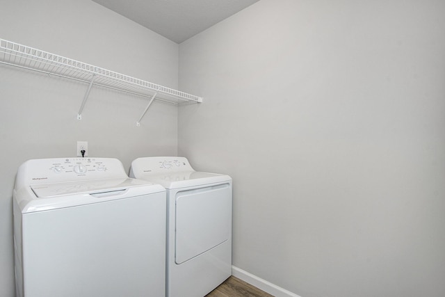 washroom with wood finished floors, independent washer and dryer, laundry area, and baseboards