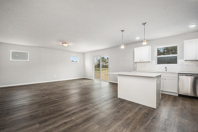 kitchen with stainless steel dishwasher, light countertops, a center island, open floor plan, and dark wood-type flooring