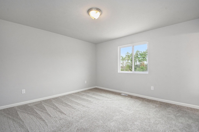 carpeted spare room featuring visible vents and baseboards