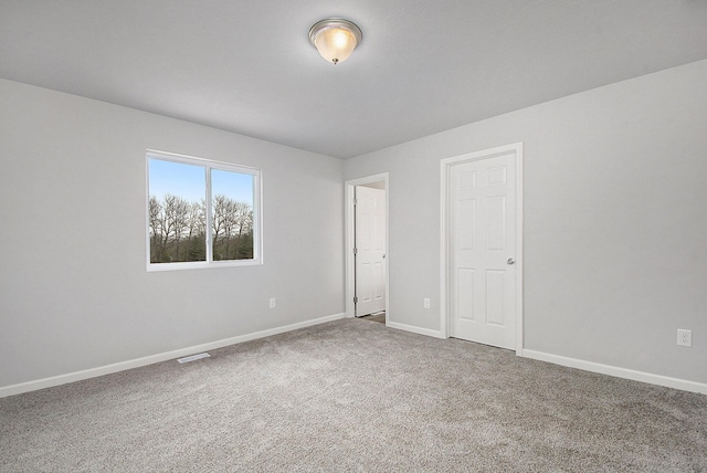carpeted spare room featuring visible vents and baseboards