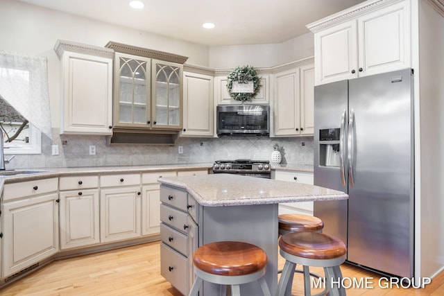 kitchen featuring a kitchen island, tasteful backsplash, light hardwood / wood-style floors, a kitchen bar, and stainless steel appliances